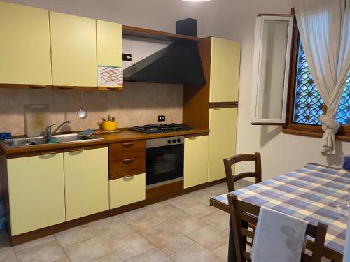 a kitchen with yellow cabinets and a table with a table cloth at Il Ronchetto in Sorso