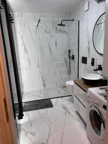 a white bathroom with a shower and a sink at Piła- balkon-3 osoby-2 łóżka-przytulny apartament in Piła