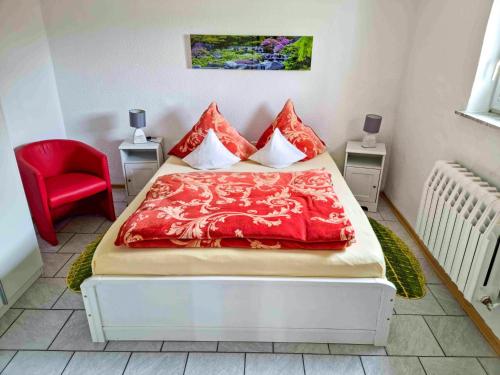 Schlafzimmer mit einem Bett mit roter Bettwäsche und einem roten Stuhl in der Unterkunft Ferienwohnung in Kenz-Küstrow in Barth