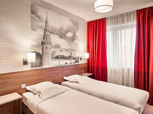 a bedroom with two beds and a painting of a church at Adagio Moscow Kievskaya in Moscow