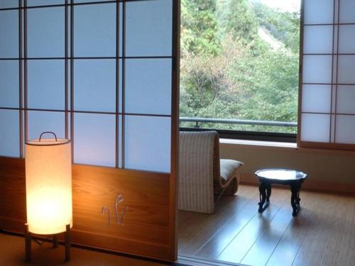 a room with a lamp and a table and a window at Ryokan Sumiya Kihoan in Kameoka