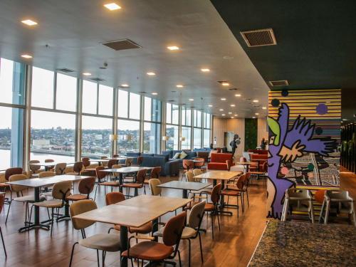 um restaurante com mesas, cadeiras e janelas em Novotel Puerto Montt em Puerto Montt