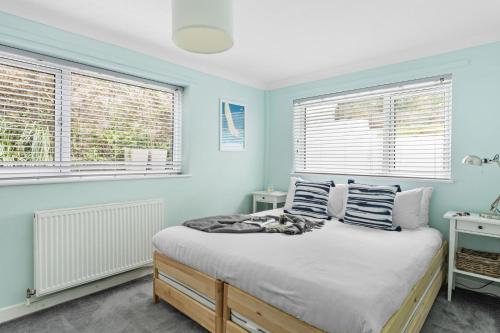 een slaapkamer met blauwe muren en een bed met 2 ramen bij The Retreat, Brixham in Brixham