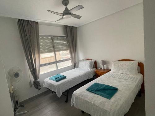 two beds in a room with a window at Lo Pagan Beachfront Aircon Apartment in San Pedro del Pinatar