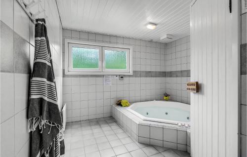 baño de azulejos blancos con bañera y ventana en 4 Bedroom Cozy Home In Blvand en Blåvand