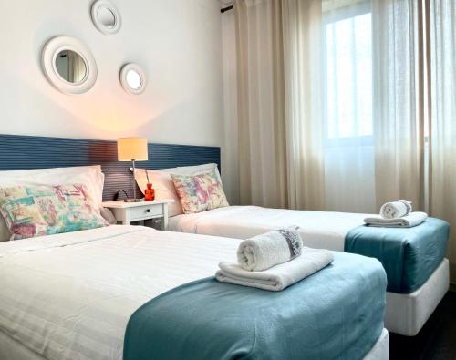 1 dormitorio con 2 camas y toallas en reposapiés en ABC Expo Apartment, en Lisboa