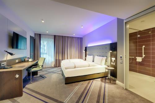a hotel room with a bed and a desk at Premier Inn Düsseldorf City Friedrichstadt in Düsseldorf