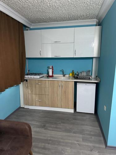 eine kleine Küche mit weißen Schränken und blauen Wänden in der Unterkunft YAKAMOZ 27 SUİT APART in Bursa