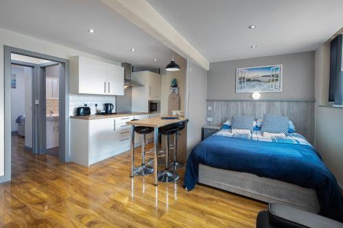 a bedroom with a blue bed and a kitchen at Seaside Suites Superior Family Apartments in Blackpool