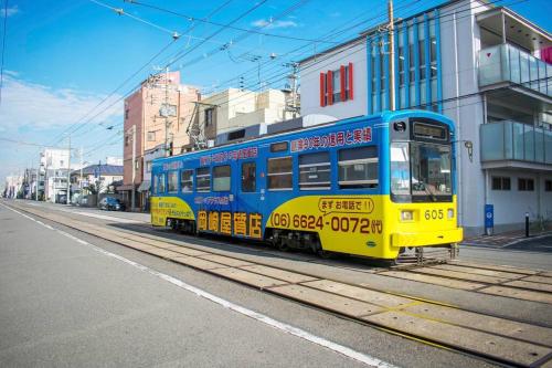 a blue and yellow train on a city street at 帝塚山忍者屋敷 in Osaka