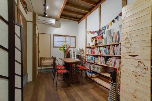 um quarto com uma mesa e uma estante de livros com livros em 帝塚山忍者屋敷 em Osaka