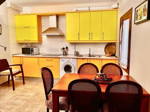 una cocina con armarios amarillos y una mesa con sillas en Casa Rural "Calle Real" en La Vera, en Villanueva de la Vera