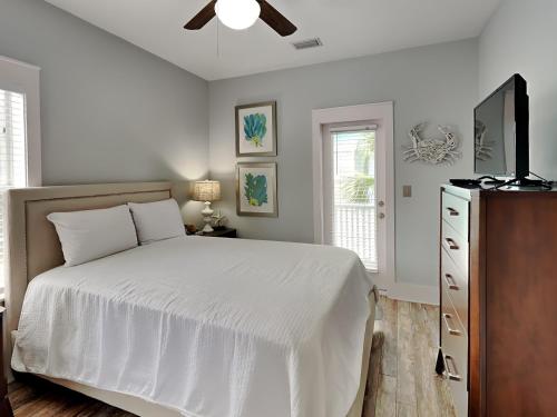 a bedroom with a white bed and a ceiling fan at Bungalows At Seagrove 149 - Three Little Birds Bungalow in Seagrove Beach