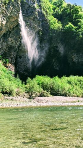 a waterfall on the side of a mountain next to a river at Museo Ostello in Ospitale di Cadore