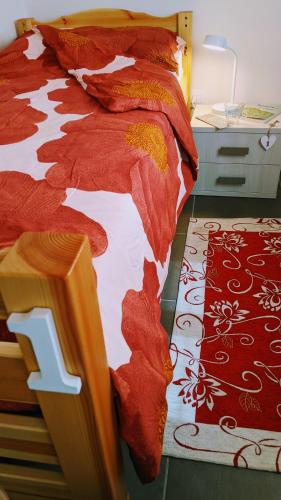 a bedroom with a bed with red sheets and a rug at Museo Ostello in Ospitale di Cadore