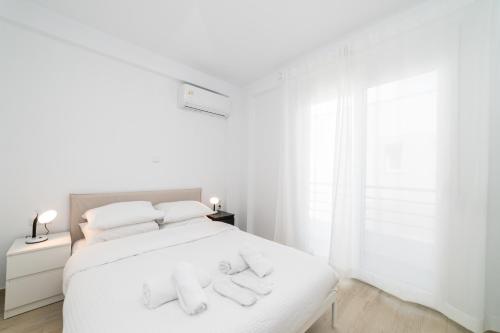 a white bedroom with a white bed with two towels on it at Nefeli & Nefeli Luxury Residential Complexes in Ofrínion