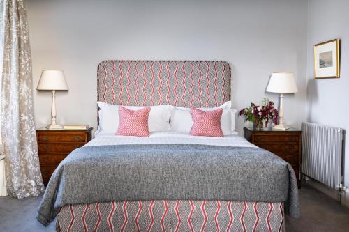 a bedroom with a large bed with pink pillows at Ballymaloe House Hotel in Ballycotton