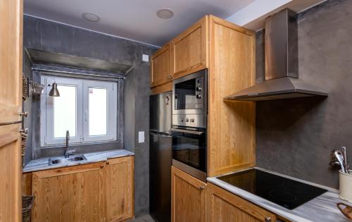 a kitchen with wooden cabinets and a sink and a window at Kais do Sol in Setúbal