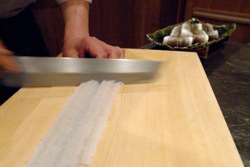a person holding a knife on a cutting board at Ryokan Sumiya Kihoan in Kameoka
