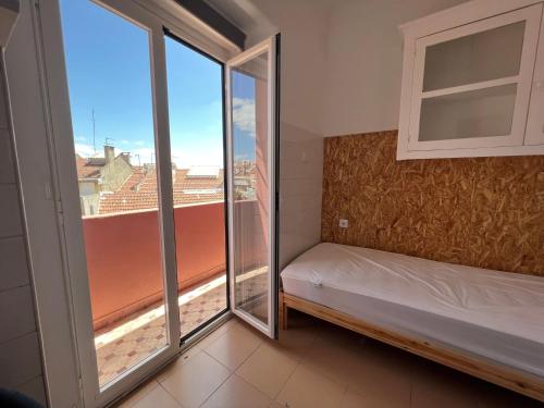een kleine kamer met een bed en een raam bij Olaias13 in Lissabon