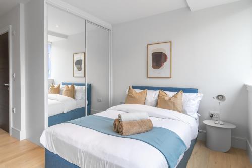 Schlafzimmer mit einem blauen und weißen Bett und einem Spiegel in der Unterkunft Livestay-Modern Apartments Next To Wembley Stadium in London