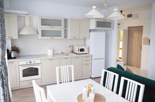 eine Küche mit weißen Schränken sowie einem Tisch und Stühlen in der Unterkunft Elis Apart in Oradea