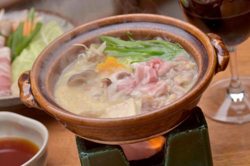 a bowl of soup on a table with a glass of wine at Ryokan Sumiya Kihoan in Kameoka