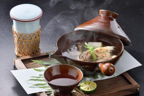 a wooden tray with a pot of food and a drink at Ryokan Sumiya Kihoan in Kameoka
