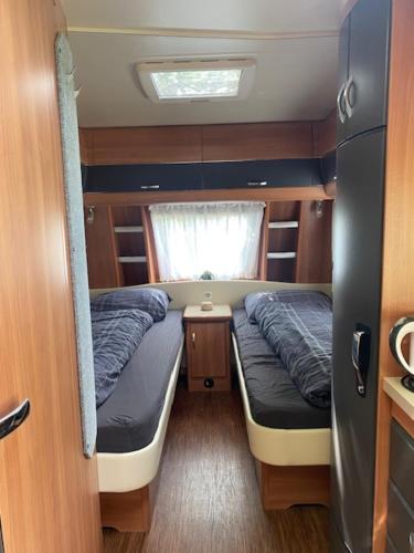 a small room with two beds and a window at Caravan op Camping t Kopske in Den Hout in Den Hout