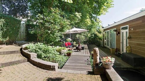 a backyard with a wooden deck with an umbrella at Benedenverdieping in Woonboot met tuinterras in Utrecht