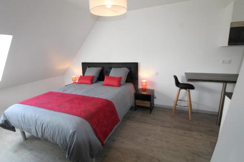 Schlafzimmer mit einem Bett mit roten Kissen und einem Schreibtisch in der Unterkunft Chambre salle de bain wc et cuisine privé proche centre ville in Loudéac