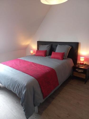 une chambre avec un grand lit avec deux oreillers rouges dans l'établissement studio ouest cuisine privé proche centre ville, à Loudéac