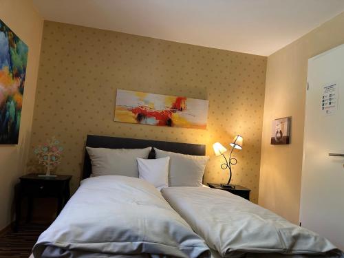 a bedroom with a large bed with white sheets at Maier Pension in Bayerisch Eisenstein