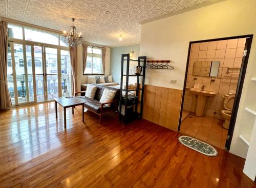 una sala de estar con suelo de madera y una habitación con una silla y una mesa. en Gift Box Hostel en Chishang