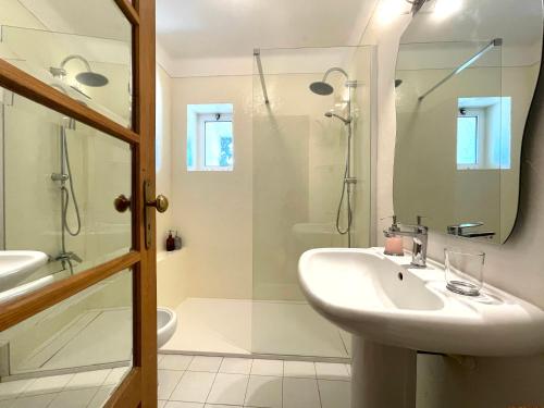 a white bathroom with a sink and a shower at Sea House in Viana do Castelo