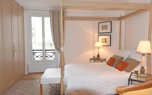 une chambre avec un lit à baldaquin et une fenêtre dans l'établissement Sophisticated Gem in the Heart of Paris - 107m2, à Paris