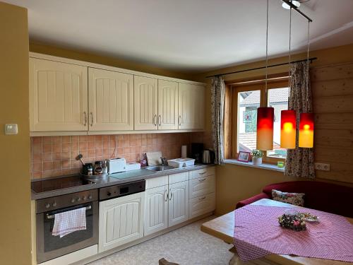 a kitchen with white cabinets and a table and a window at Maier Chalet in Bayerisch Eisenstein