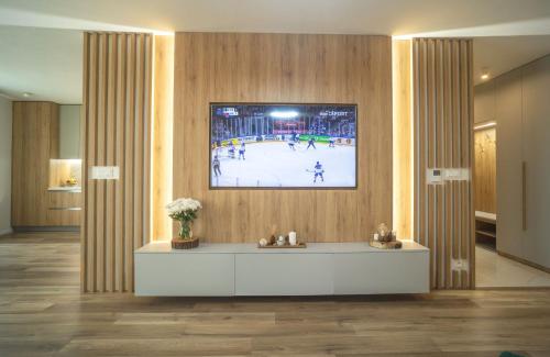 a lobby with a tv on the wall with a hockey game at Po City Newly Built Apartment in Prešov