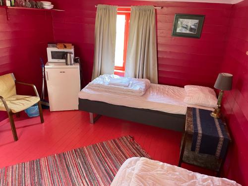 a red room with two beds and a window at Kræmmervika Rorbuer - Rustic Cabins & Hostel in Lofoten in Ballstad