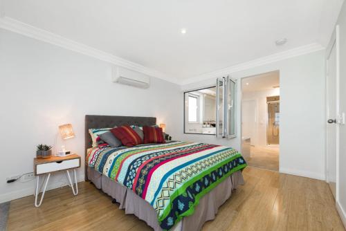 um quarto branco com uma cama, uma mesa e uma janela em Oceans Waves - Luxury Apartment with ocean views em Lancelin