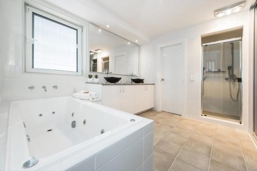 uma casa de banho branca com uma grande banheira e um chuveiro em Oceans Waves - Luxury Apartment with ocean views em Lancelin