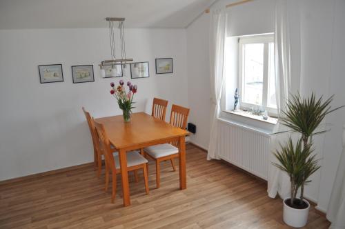a dining room table with chairs and a vase of flowers at Meerblick Apartment in Göhren