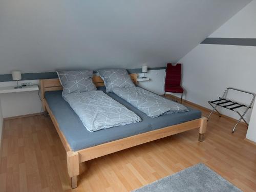 a bed in a small room with a red chair at Ferienwohnung Frühlingstraße in Mehlbach