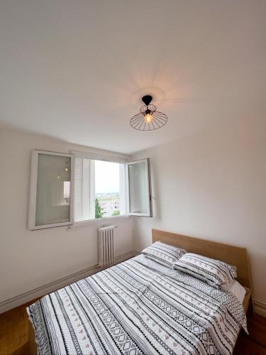 um quarto com uma cama, uma ventoinha de tecto e uma janela em APPARTEMENT SPACIEUX AVEC BALCON em Saint-Fons
