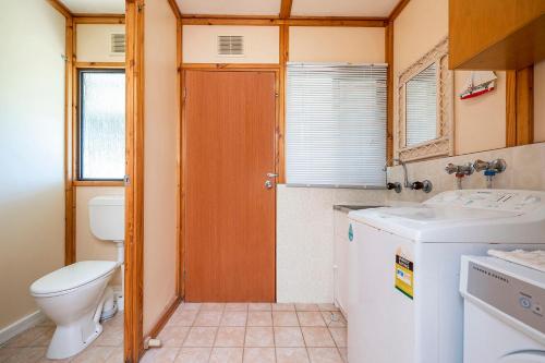 a bathroom with a toilet and a washer and dryer at Sea Breeze - Perfect house for the family in Lancelin