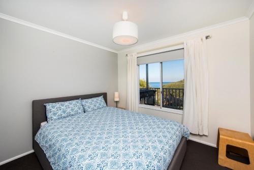 a bedroom with a bed and a window at Seaclusion Cottage - Modern renovated beach house in Guilderton