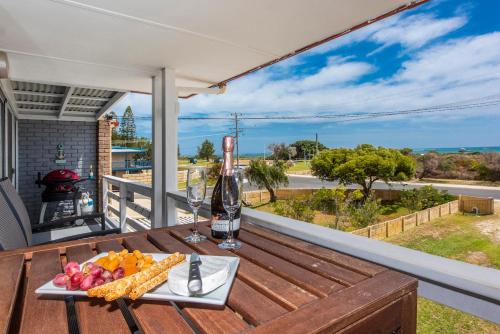 a table with a bottle of wine and fruit on a balcony at Sunset View- Ocean Views in Lancelin