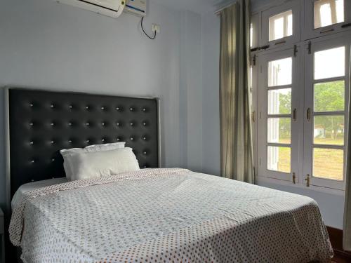 una camera da letto con letto con testiera nera e finestra di Gracia Locus- Home Comfort a Dimāpur