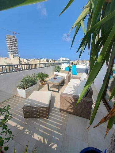 a patio with chairs and tables on a roof at the Queen Freddy Penthouse in Taʼ Xbiex