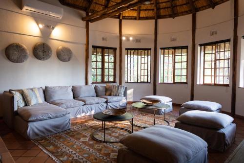a living room with couches and tables and windows at MILIMA Big 5 Safari Lodge in Hoedspruit